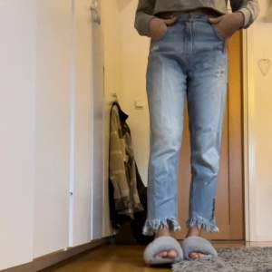 Ett par ankellånga ljusblåa jeans från Zara i storlek 36. Jeansen har slitningar, fransar nertill, fickor baktill, och text på höger ben, ”overdressed”. Köparen står för frakten💗 