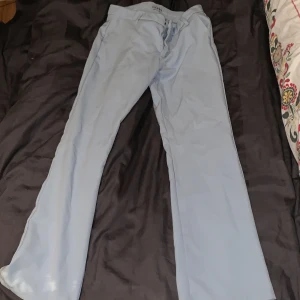 Kostymbyxor - Ett par ljusblå kostymbyxor som krympt i tvätten, använda en gång, sitter väldigt bra på benen och baken. Ordinarie pris 400.