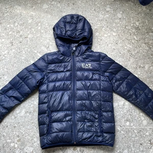 EA7 Dunjacka - Säljer för att den ej passar längre. Den är använd men i bra skick utöver ett litet hål i armen. (Se bild2) köpt för 1299 kr