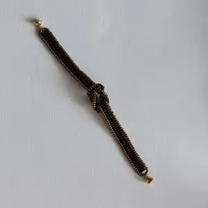Ett egentillverkat armband av miyuki seed beeds i svart och brons Med en knut på mitten och magnetlås  Armbandet är 12mm brett, knuten 3×2cm Och är 18,5cm långt, mönstret hämtat från Youtube  Frakt 13kr