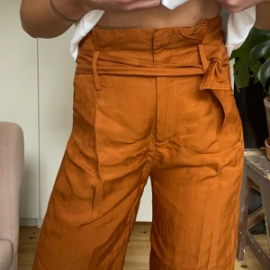 Orange/bruna croppade byxor från & Other Stories - Knytbara höga byxor från &Other Stories. Bild 2 bäst i färgen, dom är lite rostfärgade. Slarvade med att steama dom desvärre. Svinsköna sommarbrallor!