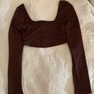 Brun Bershka crop top - fin tröja från Bershka, har köpt secondhand men har aldrig använt den och den är i väldigt fint skick! har en detalj vid bröstet. Jag kan träffas och lämna den om du bor i Nacka eller kan komma till Nacka.