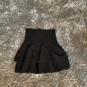 Svart kjol - Säljer denna kjol från Gina tricot ”Lizette smock skirt”, köptes från zalando🌟jättesöt kjol som även går att ha som topp, är även bra i längden för mig som är 173🫶 använd fåtal gånger så i bra skick, säljer då den inte kommer till användning💞