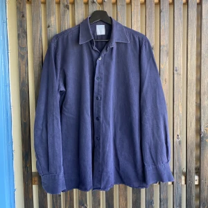 Mörkblå skjorta  - Mörkblå skjorta med inget märke i storlek L. Ett litet hål på baksidan (bild 3). Pris: 199kr