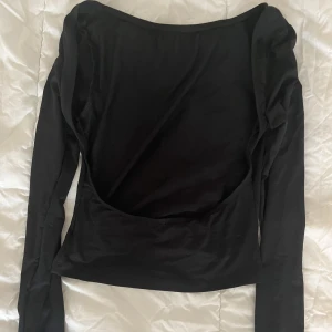 Svart tröja med öppen rygg - Aldrig använd, endast testad.  Svart tröja, kort, långärmad & öppen i ryggen.   