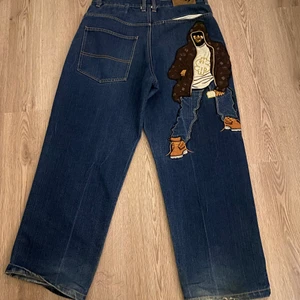 Baggy jeans med broderi - Raw blue jeans från 2000-tal,har inte hitta några exak likadana någon stans så dem är väldigt ovanliga. Byxorna är i bra skick men har heal drag längs ner. Dem sitter bra på personer som är typ mellan 170-180 cm långa.  Midian är 86 cm. 