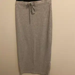 En grå ribbad kjol som är lite längre än till knäna och går att knyta i midjan.
