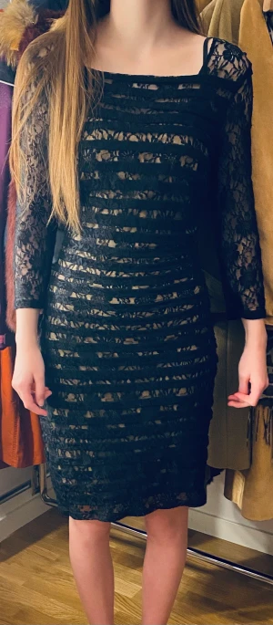 Svart spets klänning med stretch - Läcker festklänning, lagom längd just ovanför knäna. Beige undertill och svart spets ovanpå. Square urringning. Långärmad.