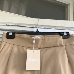 LÄDER (faux) byxor STYLEIN - Läderbyxor (ej äkta läder, vegansk konstskinn) från Stylein säljes. Beige, svinsnygg till våren. Helt ny med prislapp. Säljes pga garderobsrensning, storlek: S.   Modell på byxorna: Vivien.   Spårbar frakt: 66kr. 