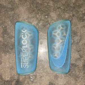 Benskydd  -  Nike Benskydd Mercurial Flylite Superlock New Lights-blå/vit. Slutsålda benskydd som endast ör använda fåtal gånger. 