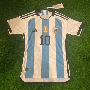 Argentina fotbollströja-Messi 10 - Hej! Säljer denna Argentina fotbollströja, den är aldrig använd och lappen sitter kvar. Alltså 10/10 i skick. Tröjan är i storlek small med Messi 🐐nummer 10 på ryggen. Skicka ett meddelande ifall ni har några funderingar👍