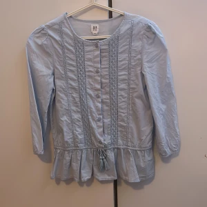 GAP blus - Oanvänd GAP blus. Storlek XXl i barnavdelningen så passar xs/xxs. Fin ljusblå färg med fina volanger nertill. Perfekt till skolavslutning💗