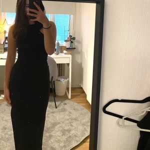 Svart långklänning med slits  - Säljer denna svarta långklänning med slits från Bershka. Klänningen är i storlek S och går strax över anklarna på mig som är 164 cm lång. Endast använd vid ett tillfälle. 