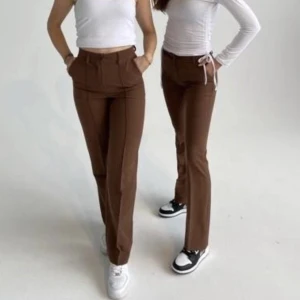 Bruna Kostymbyxor - Ett par bruna kostymbyxor från design by si, ganska stora för sin storlek som egentligen är xs men passar bättre som S som jag vanligtvis har, ordinarie pris 529 kr, säljs för 250+ frakt