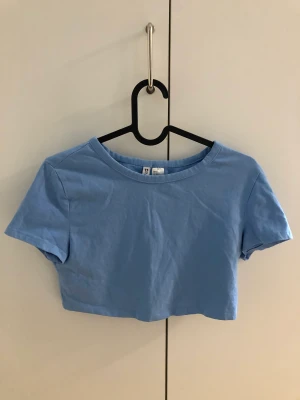 Croppad t-shirt - Helt oanvänd croppad t-shirt från H&M💙Jag är XS och tycker storleken M ändå såg snygg ut på mig! Säljer pga jag inte använder den