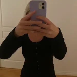 En svart tröja med knappar från Nelly.Com i storlek S
