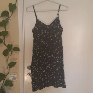 Blommig klänning  - Knut/rosett framtill, stretch baktill.  Banden är justerbara.