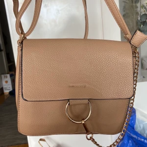 Beige axelväska - En mindre beige väska med guldiga detaljer i bra skick. Lång och justerbar axelrem, köpt utomlands för något år sedan☺️