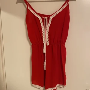 Röd byxdress  - Röd byxdress med vita detaljer. Köptes på en marknad i frankrike, använd fåtal gånger. Nyskick! Jag har kortat axelbanden men det går att enkelt sprätta upp :)
