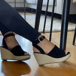 Svart kilklack stl 36 - Svart kilklack från Pace, helt oanvända men väldigt bekväma. Rotting detaljer på klacken.