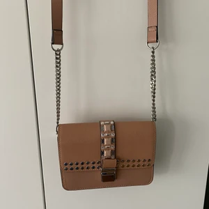 Hm väska  - Hm väska i beige med nitar och strass/stenar. Fint skick då den används fåtal gånger.