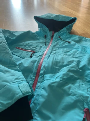 Skidjacka Five Seasons - Turkos skidjacka med många bra fickor. Ventilationsdragkedjor i sidan. Sköna muddar vid ärmslut..  HTC 50000 Fint skick!  Storlek 38 men upplevs som ganska liten så snarare XS. 