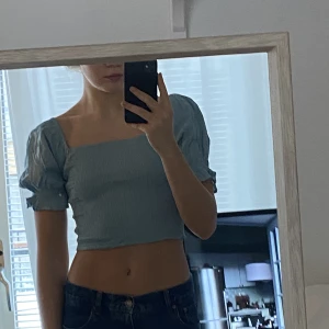 Blå topp - Blå sommartopp med puffärmar. Väldigt fin och somrig. Endast använd 1 gång så i bra skick. Väldigt flexibel i strl pga stretchtyg.