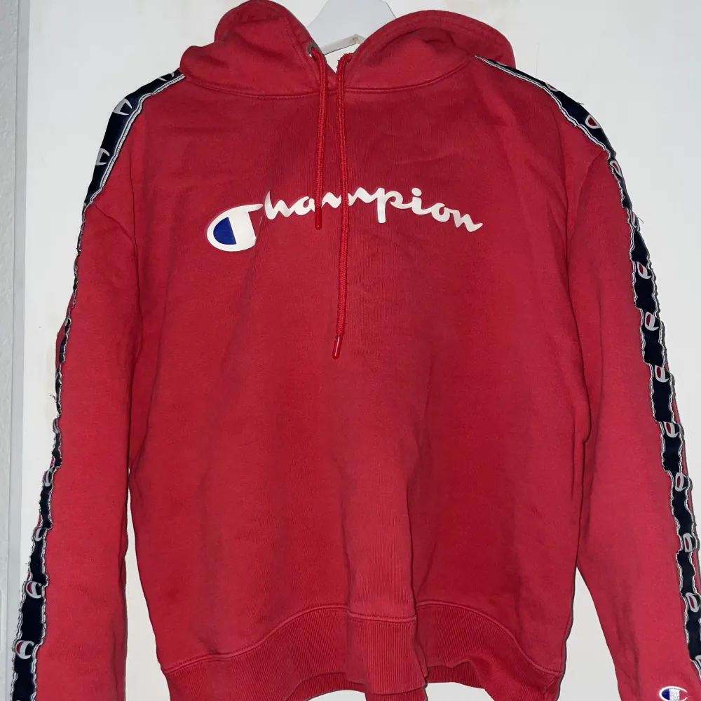 Röd champion hoodie med loggan längs ärmarna. Köpt från JD Sports men minns ej originalpriset. Skriv för mer bilder. Hoodies.