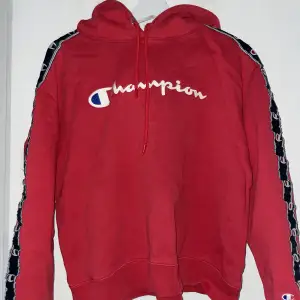 Röd champion hoodie med loggan längs ärmarna. Köpt från JD Sports men minns ej originalpriset. Skriv för mer bilder