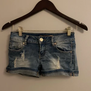 Jenansshorts - Jeansshorts med slitning framtill och diamantdetaljer på knapparna. Mycket stretchiga  Köpare står för frakt