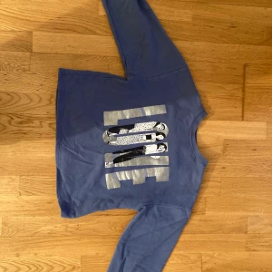 Blå Tröja från zara  - Tröjan är blå och med silvrig text i mitten. Tröjan är lite cropped. Strolek: 11/12 år och är 152 cm. 