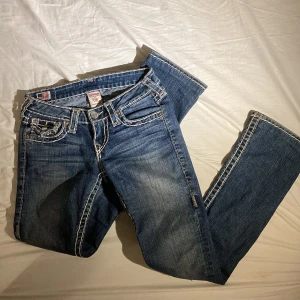 True Religion jeans strl 25 - Säljer mina True Religion ”Billie super T” jeans i strl 25 för att de blivit lite för korta. Lågmidjade och lite bootcut. Passar xs/s. Bra skick & inga defekter utom att fickorna vikt sig lite i hörnen (syns på bild 2).   Midjemått: 73 cm  Innerben: 79 cm