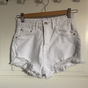 Vita jeansshorts - Vita slitna jeansshorts från Zara i storlek 34. Shortsen har ett litet blåt streck som knappt syns.