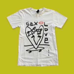 Vit tröja med tryck på - Köpt från Junkyard. Har några små fläckar på sig både fram och bak, syns knappt, fråga för närmare bilder! Materialet är bomull. Längd 65 cm, axlar 41 cm ✨ Köp nu!