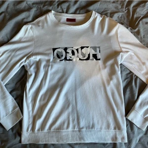 Hugo Boss sweatshirt - Tunn vit sweatshirt från Hugo (Hugo Boss) i fint skick, strl. M. Finns 2 små fläckar på övre delen av ryggen som knappt syns (se bild).  Nypris ca 1000 kr. 