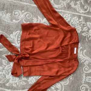 Satin topp  - Topp från mango i finaste orange färgen. Går att knyta i en rosett antigen fram eller bak. Materiellt är satin. Har endast använt den en gång 