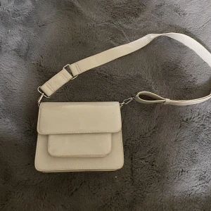 Axelväska - En blank axelremsväska i glansigt material. Bandet går att justera. Perfekt för en utekväll. 