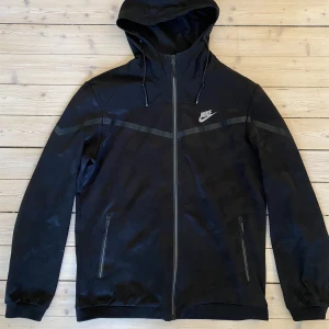 Nike tröja - Nike jacka/ hoodie. Mer som en tunnare vind/träningsjacka. Storlek L men passar M också. Svart med kamouflage mönster. Bra skick.