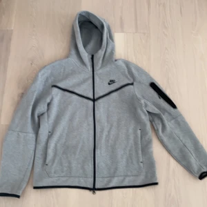 Nike tech hoodie - Säljer nu min Nike tech hoodie då den inte längre används. Köpt för cirka ett år sedan och är i bra skick förutom snöret vid tagen som är halvt sönder ( kolla sista bilden )