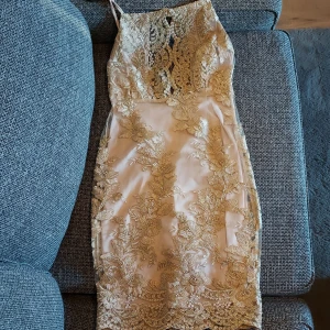 Dennis Maglic Klänning Strl. S - En fin beige/ljusrosa klänning med vackra mönster i  guld från Dennis Maglic. Storleken är S (Small)