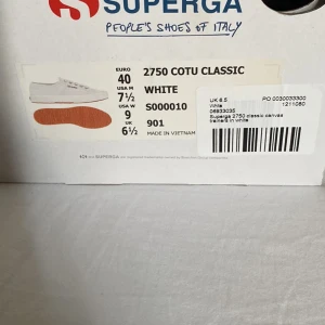 2750 Cotu Classic Superga träningsskor i vitt och guld - Vita Superga träningsskor med guld detaljer. Använda men i väldigt bra skick. Kommer med tygpåse samt i lådan med taggar