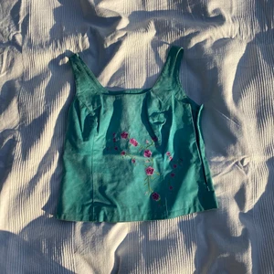 Blå topp i mocka - Supergullig topp i blå mocka med blommor på. Köpt på second hand men aldrig använd av mig. Dragkedjan funkar utmärkt!   