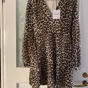 Klänning i leopard mönster - Helt oanvänd med alla lapparna kvar. Leopardmönstrad klänning med knyte i midjan. 