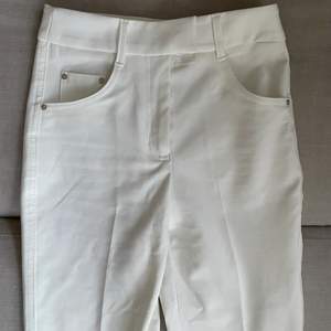 Vita bootcut kostymbyxor i stretchigt material och hög midja.  Använt men fint skick med någon synlig defekt på byxkanten då de är långa.
