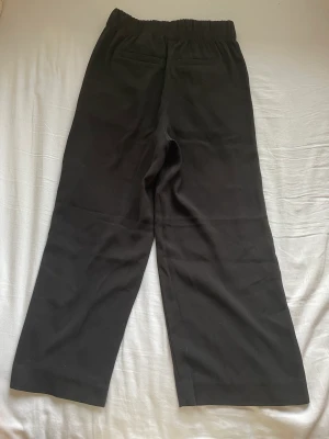 Svarta tygbyxor - Svarta byxor från H&M med fake fickor baktill