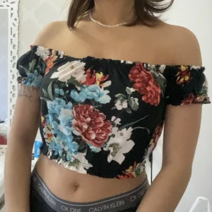 Blommig topp - Croppad topp i nyskick, man kan justera hur off shoulder man vill ha den!