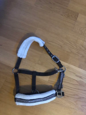 Grimma  - Säljer min grimma då den inte används längre. Använd några få gånger. Stolek: Cob Färg: brun med vitt fluff. 100 kr
