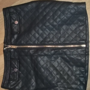 Svart kjol - Kjol ifrån bikbok i stl S I använt fint skick Fickorna fram är fejk. Färg. Svart med silverdetaljer