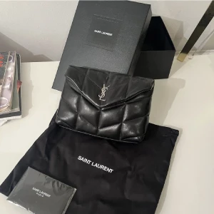 Ysl lolou puffer clutch - Säljer nu min lilla lolou puffer clutch. Endast använd en gång på min bal. Inga defekter! Super fin och man får plats med telefon, läppstift osv💕💕äkthetbevis och allt på bilden medföljer! Nypris: 8850kr