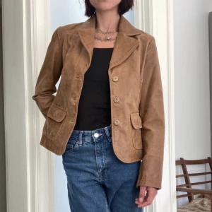 Skinnjacka 90-tal - Ljusbrun skinnjacka i jättebra skick från 90-talet. Något figursydd. Väger inte så mycket men ändå rejäl i lädret. Fina detaljer. 